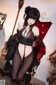 A woman in a black lingerie sitting on a red chair.