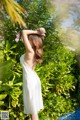 A woman in a white dress standing by a pool.