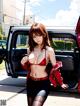 A woman in a red bikini standing next to a red car.