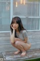 A woman sitting on a wooden bench in front of a window.