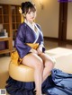 A woman in a blue and yellow kimono sitting on a yellow chair.