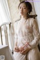 A woman in a white dress sitting on a chair.