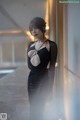 A woman in a black dress standing in a hallway.