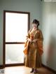 A woman in a kimono standing in front of a window.