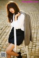 A woman sitting on a stool wearing a white shirt and black skirt.